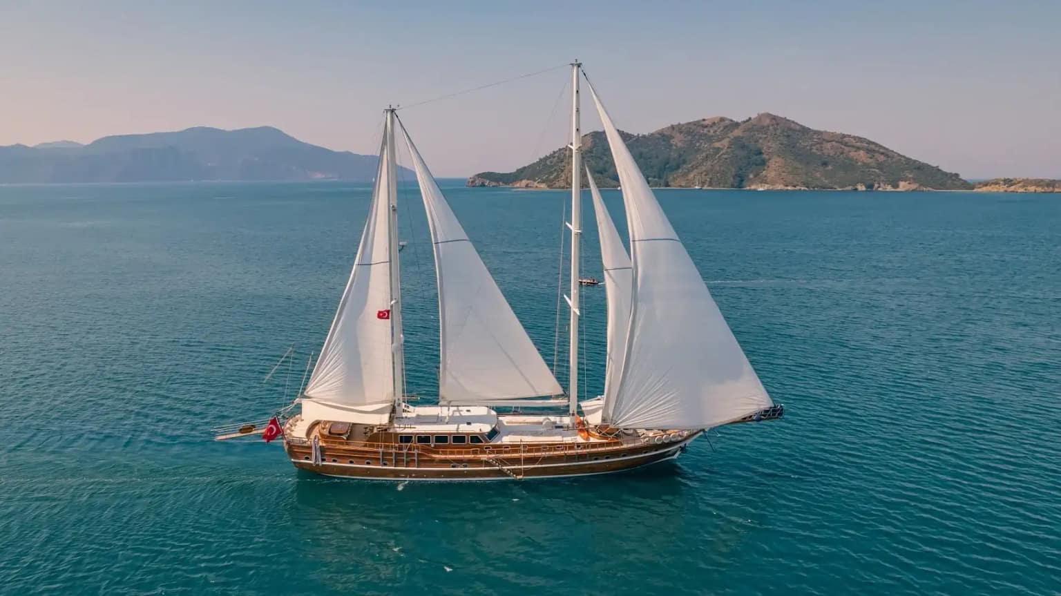 A wooden gulet anchored in a turquoise bay in Turkey.
