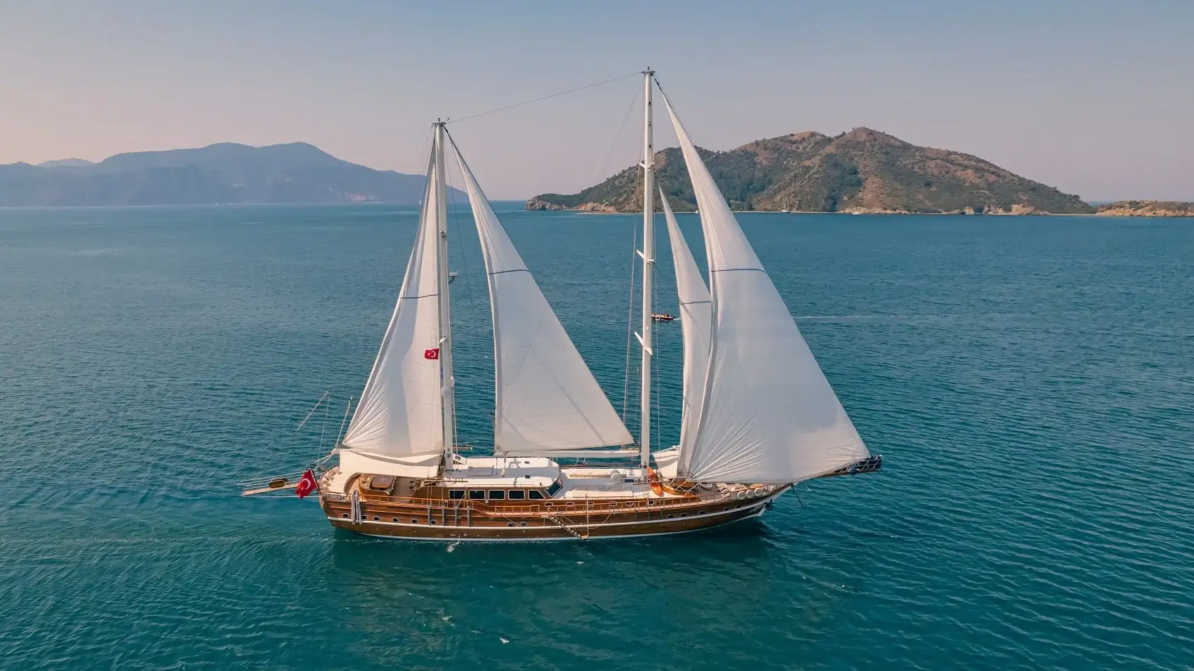 A wooden gulet anchored in a turquoise bay in Turkey.