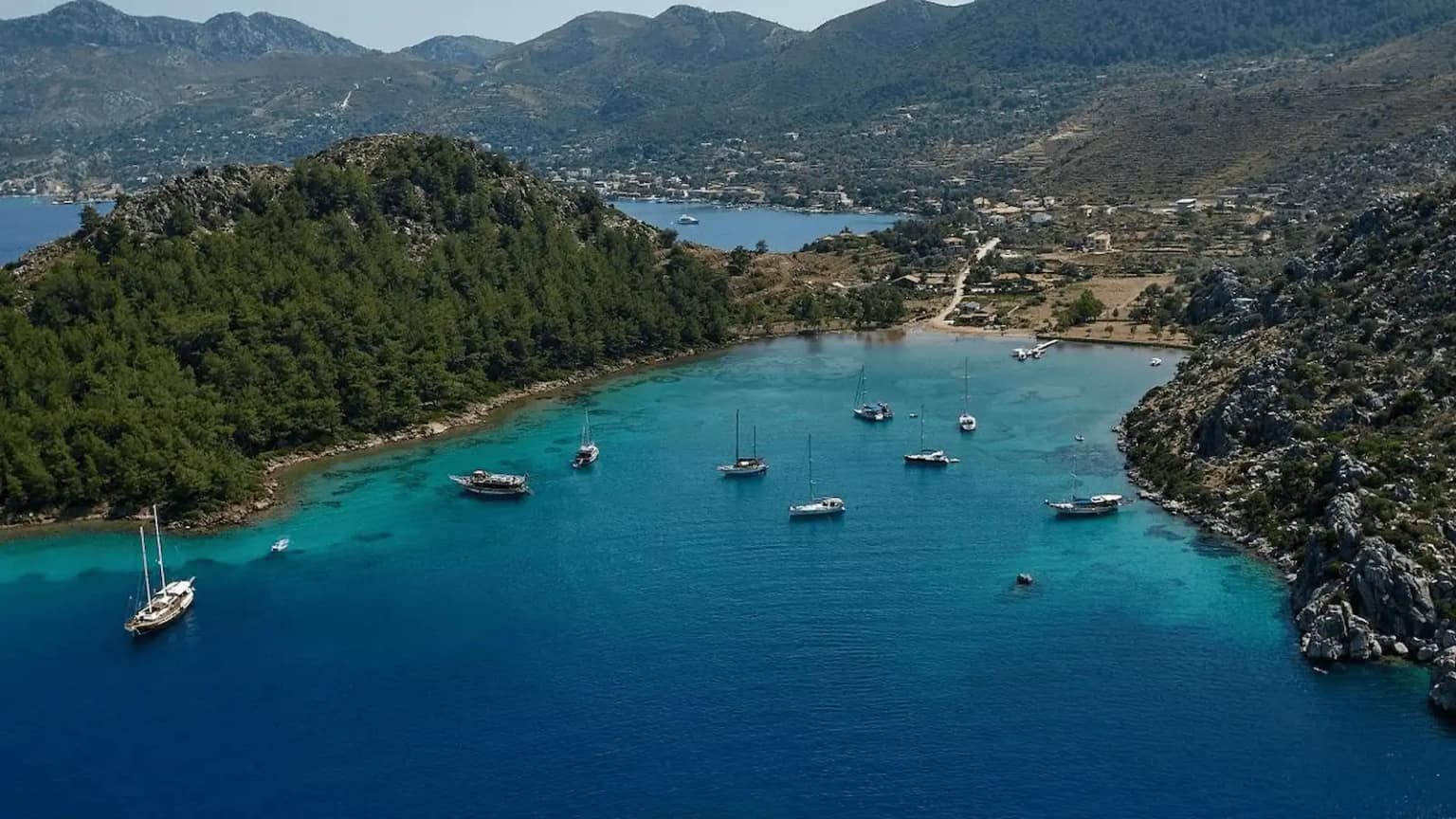 A few sailing yachts anchored off the pine-fringed beach of Cennet Koyu in Selimiye.