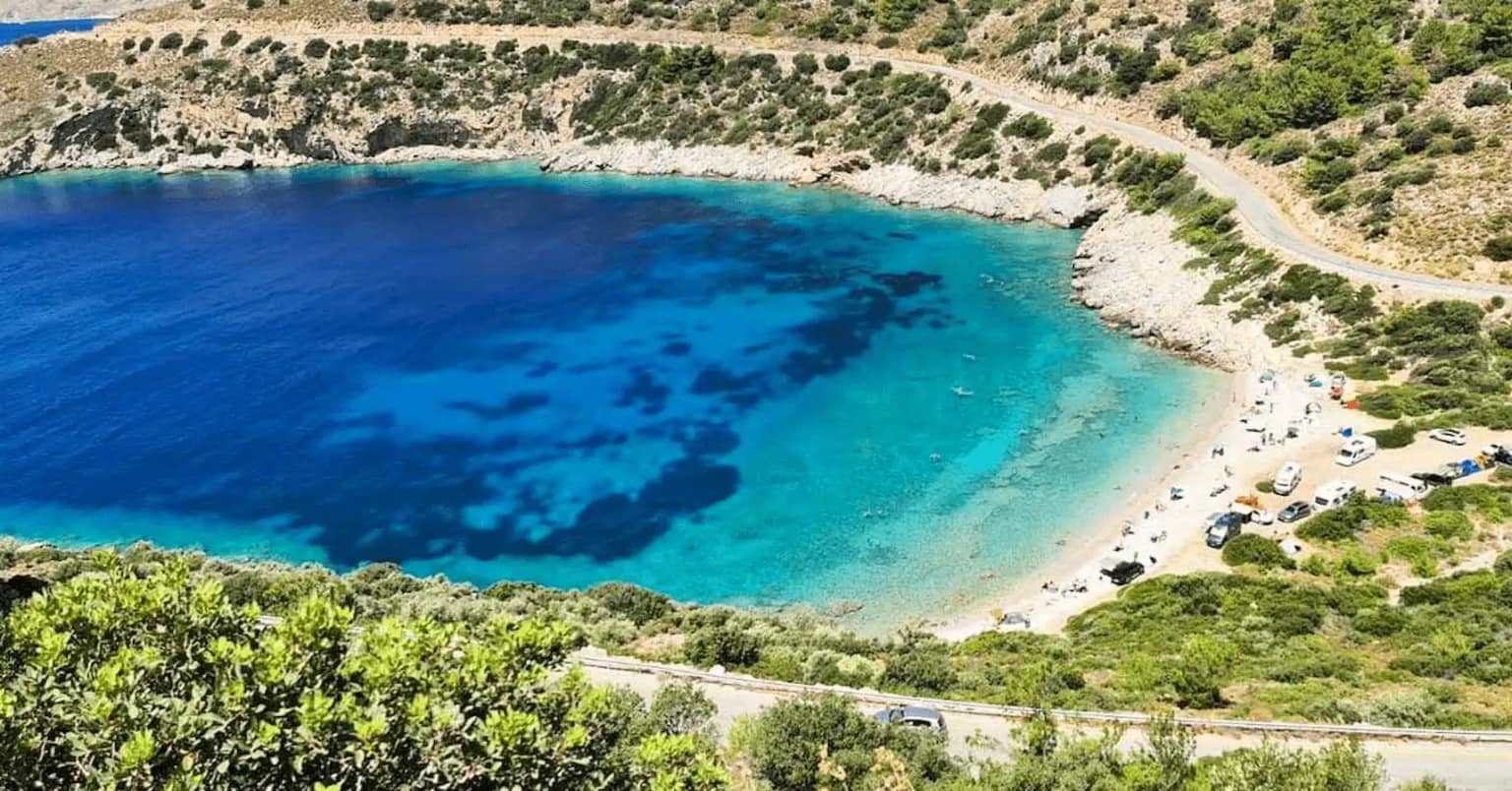 Sun loungers and small fishing boats on the beach by the turquoise sea in Palamutbükü, Datça.
