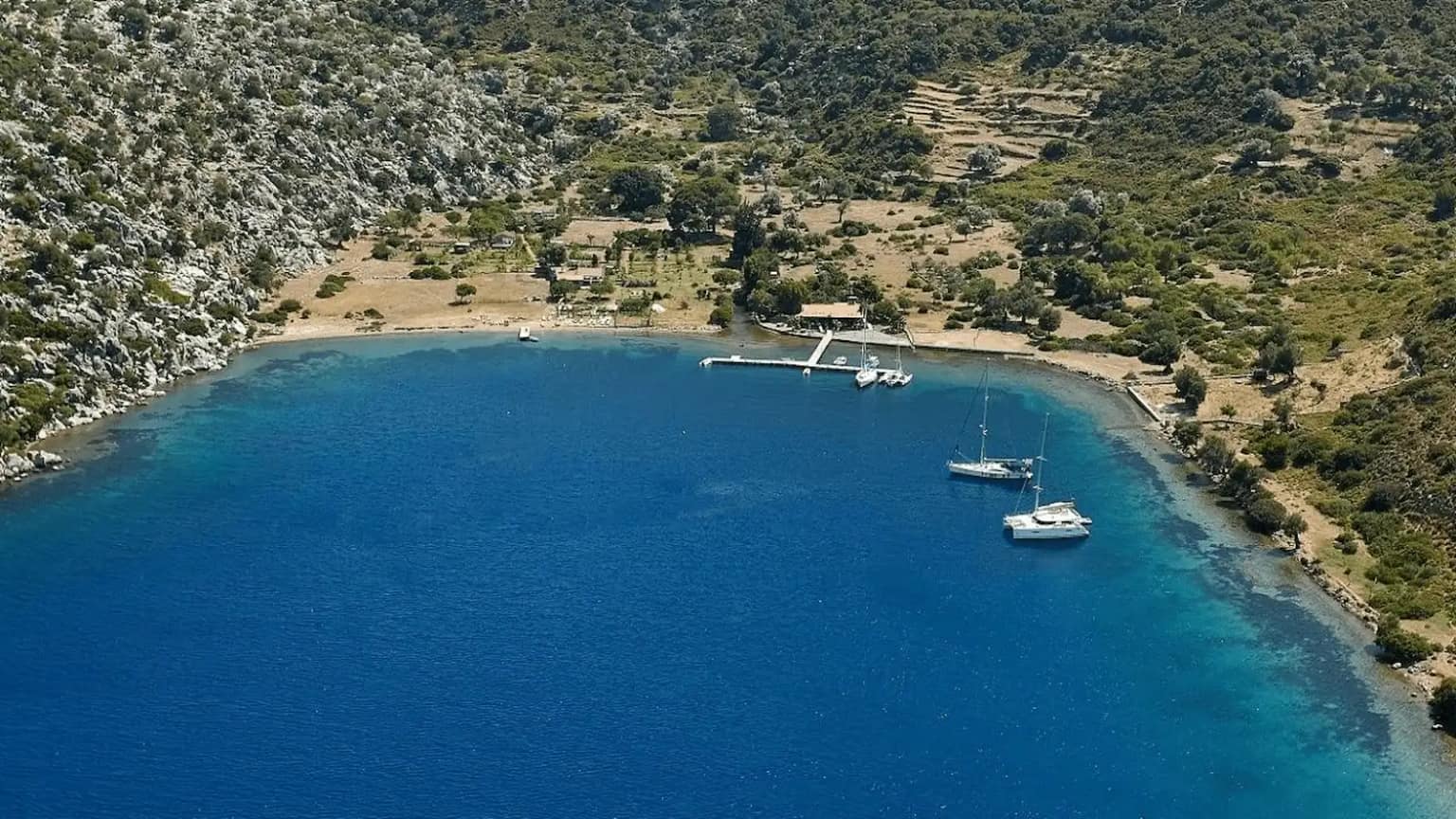 Gulets anchored in front of pine-covered mountains in Kocabahçe Bay.