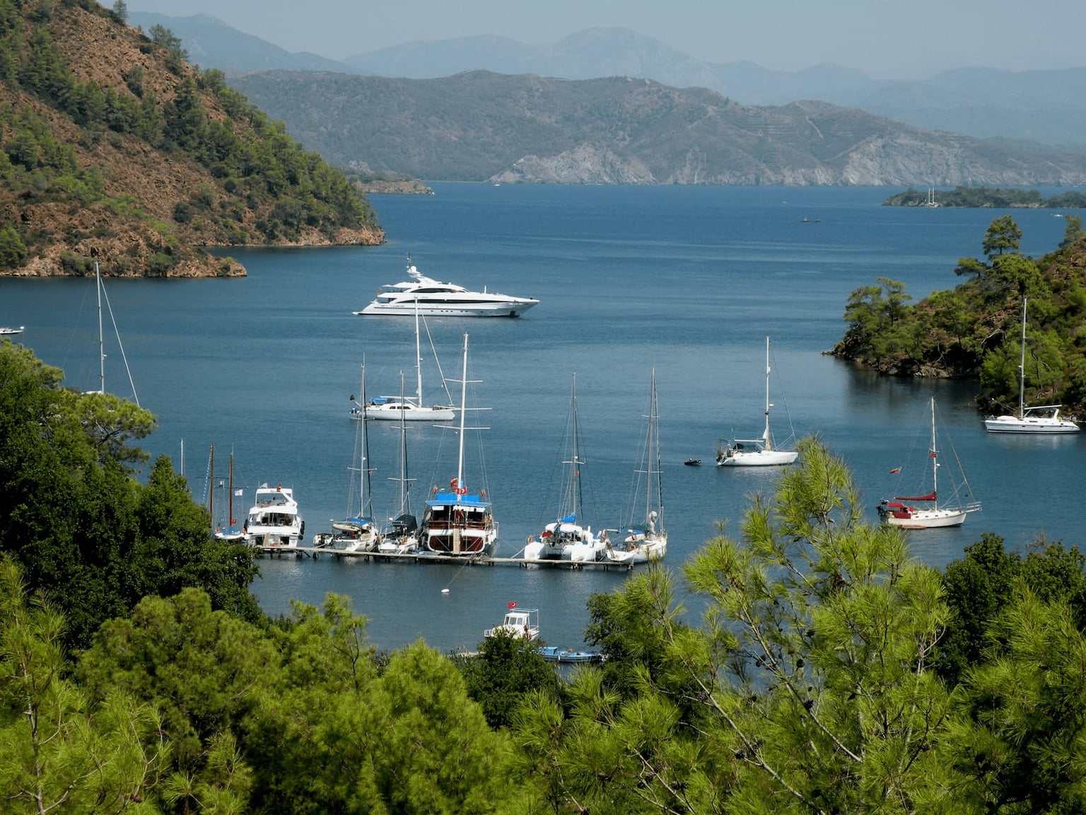 Three boats moored side-by-side in the Mediterranean, representing different rental durations.